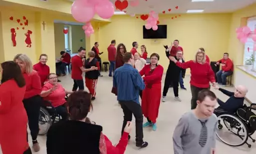 Grupa osób ubrana na czerwono tańczy na sali w WTZ