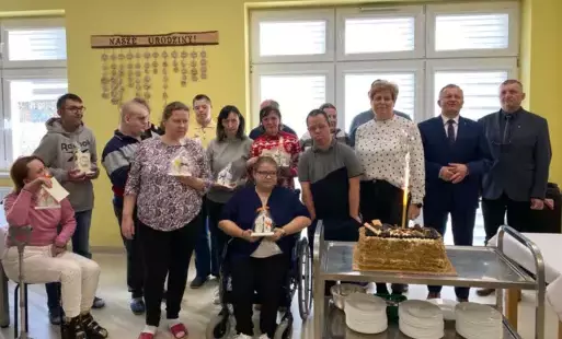 Zdjęcie grupowe solenizantów w sali WTZ na tle tortu